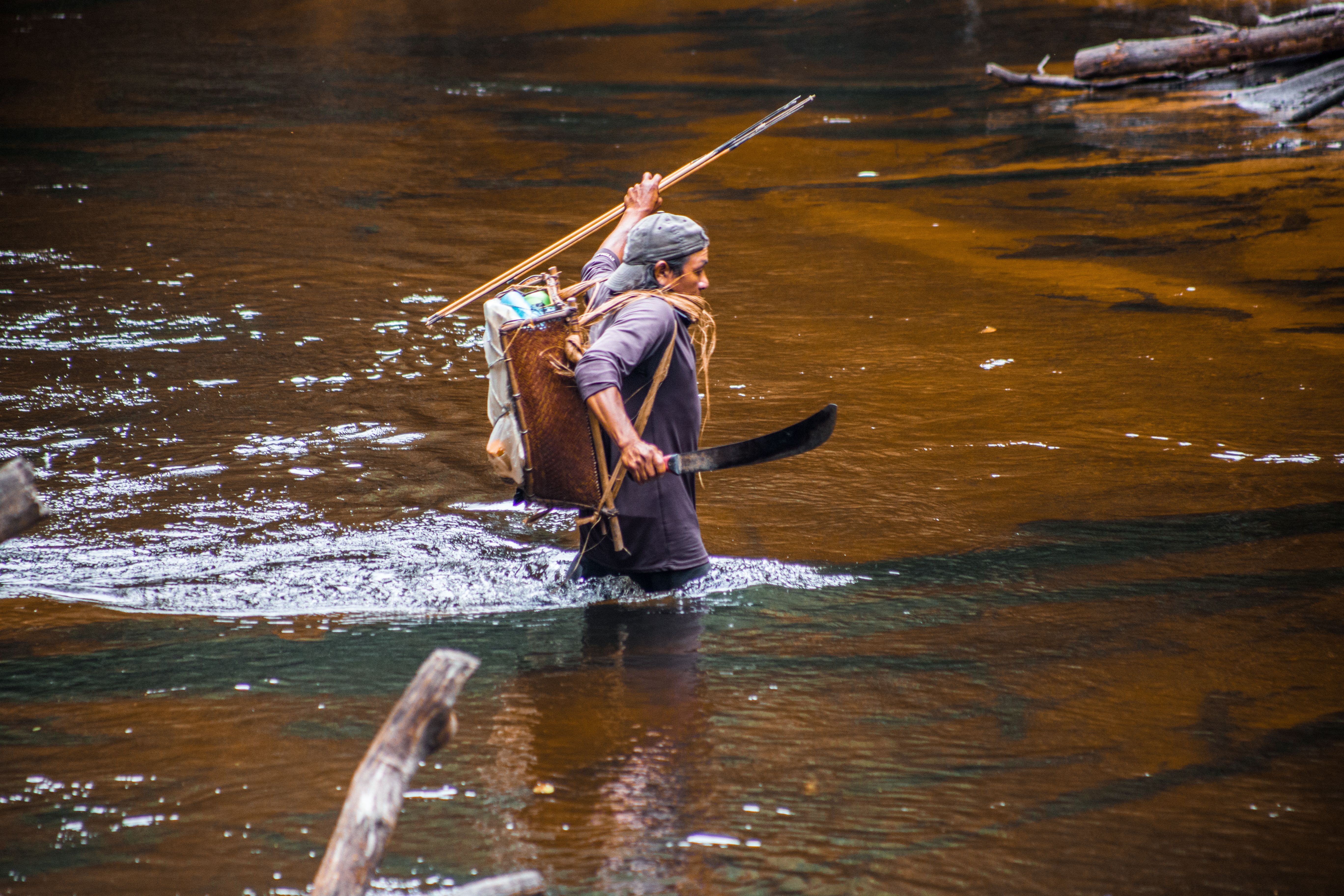 indigena en rio caminando y pescando