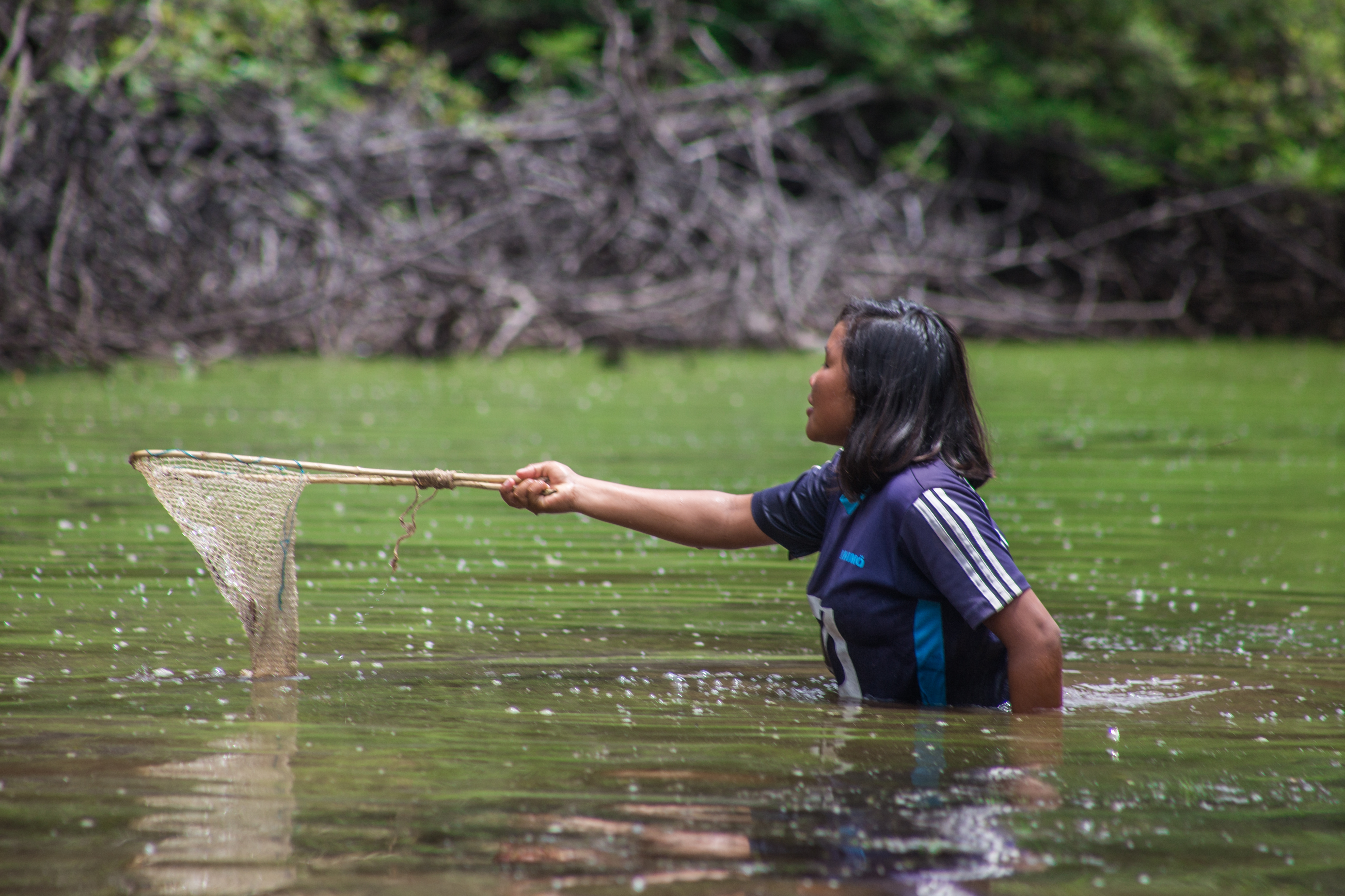 Mujer indígena pescando con red
